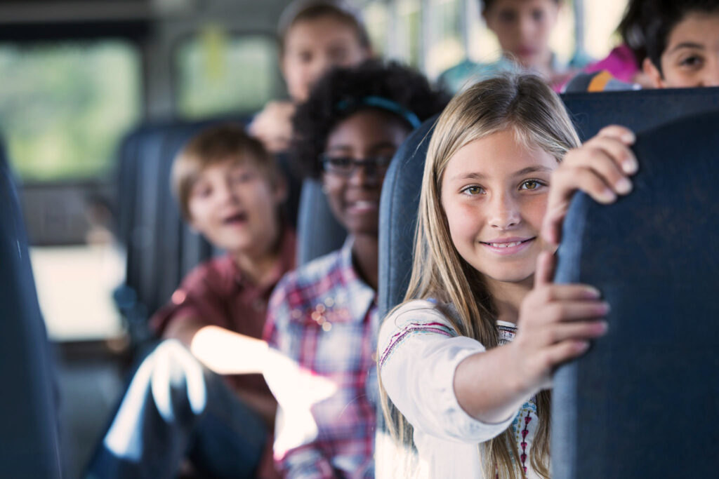 Children (10 12 years) riding school bus. Focus on girl in foregound.