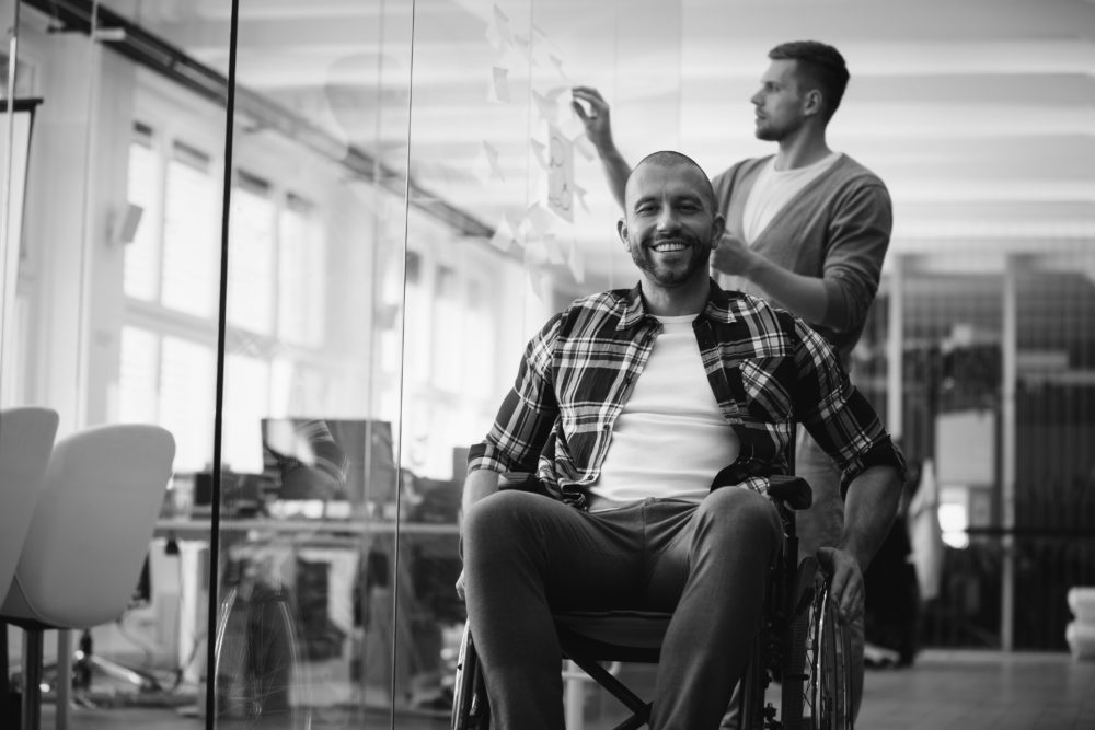 Vrolijk man in rolstoel met egeleider